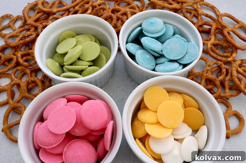 Assortment of ingredients for Springtime Pretzels: pretzels, various candy melts, and parchment paper.