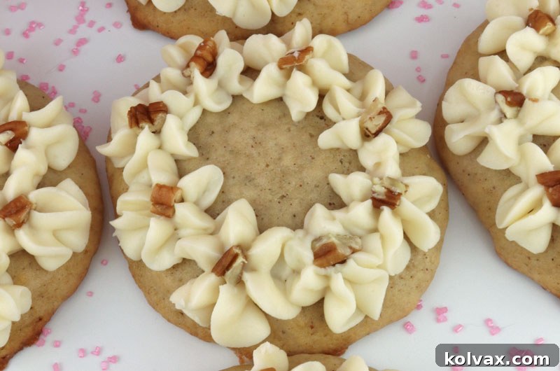 Close-up of a beautifully frosted Banana Cake Cookie, highlighting the elegant cream cheese swirl and nut garnish