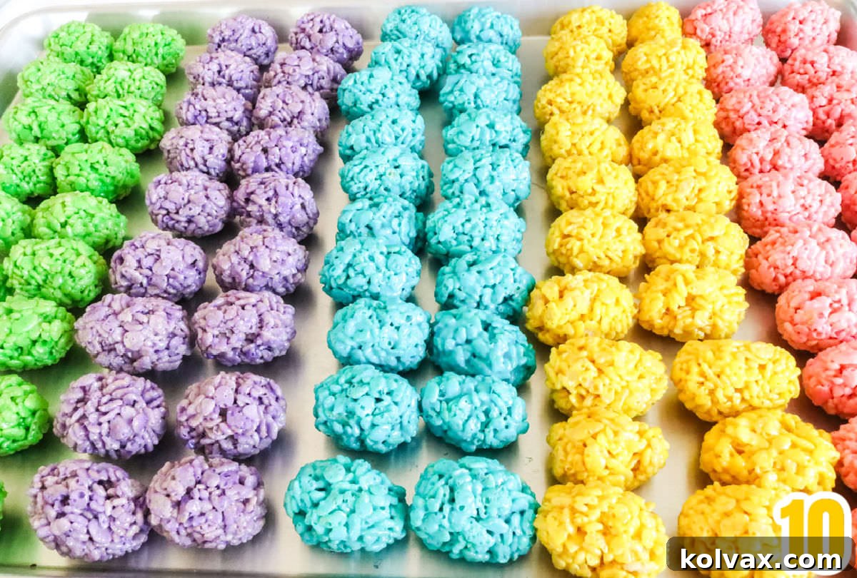 Rows of colorful Mini Rice Krispie Easter Eggs meticulously lined up on a cookie sheet, ready to be enjoyed.