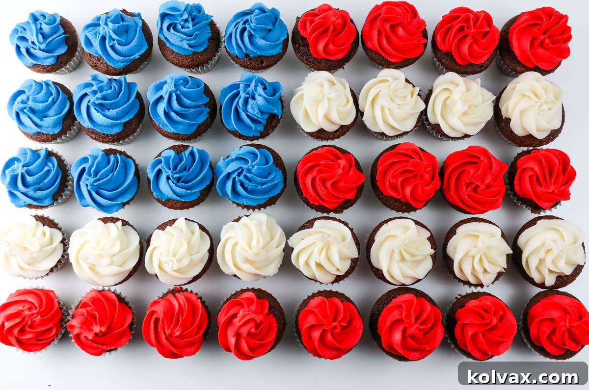 A charming overhead view of forty Red, White, and Blue Mini Cupcakes meticulously arranged to form the iconic shape of an American Flag on a pristine white table.