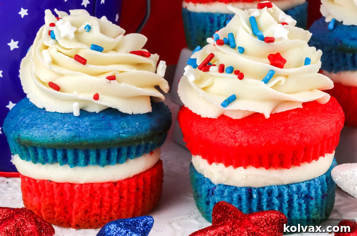 A close-up view of two stunning Red, White, and Blue Cupcakes, artfully arranged on a clean white surface amidst festive 4th of July decorations, showcasing their vibrant layers and patriotic spirit.