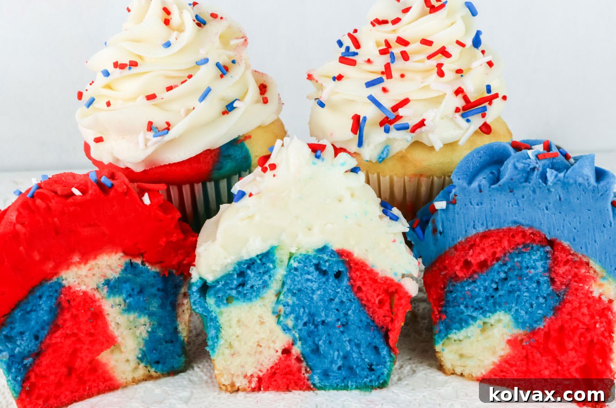 A close-up composition of five Patriotic Marble Cupcakes arranged on a pristine white table, with three cupcakes artfully sliced in half to reveal their mesmerizing marbled interior patterns.