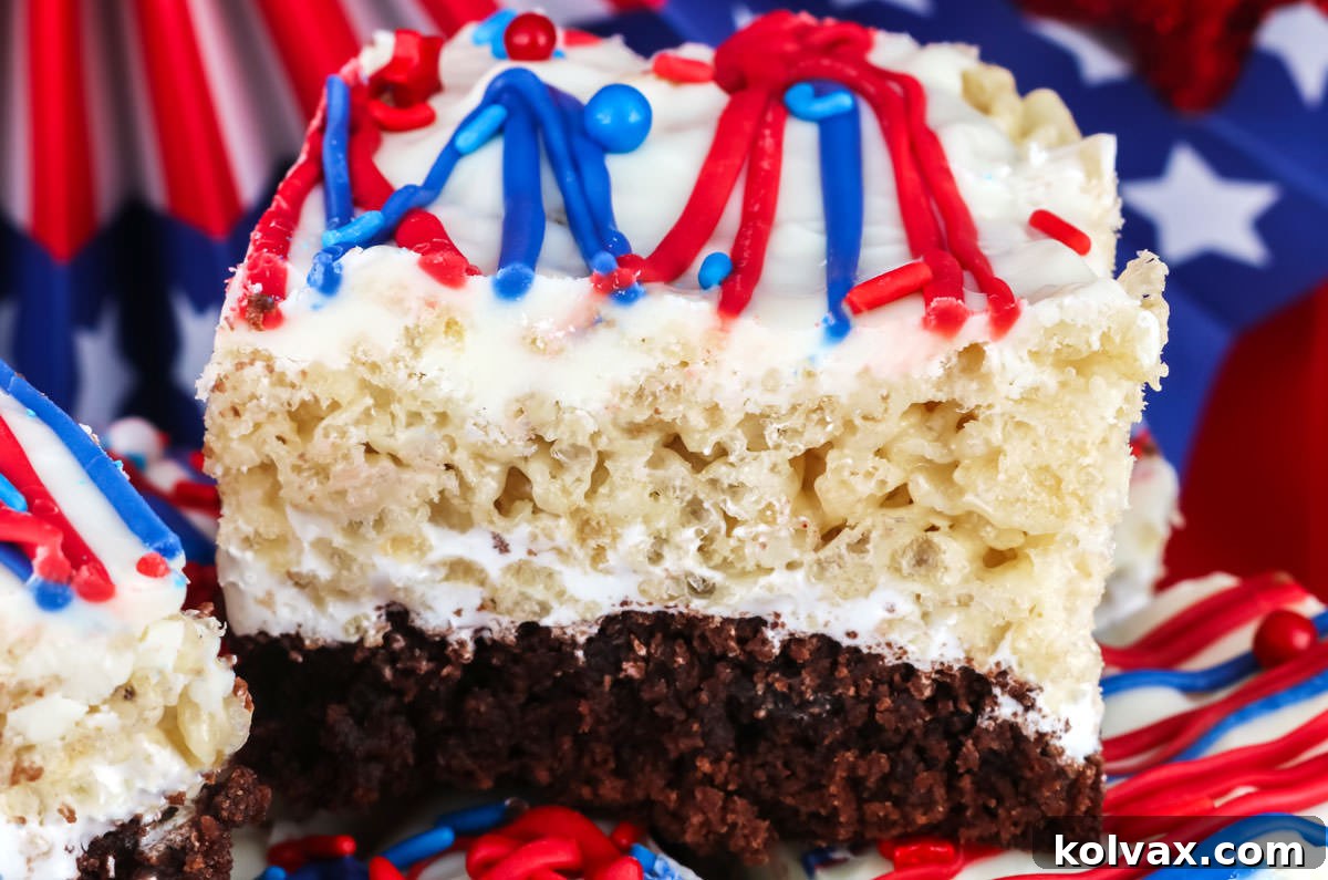 Closeup on a Patriotic Brownie Rice Krispie Treat sitting in front of 4th of July decorations, showcasing its distinct layers and festive sprinkles.