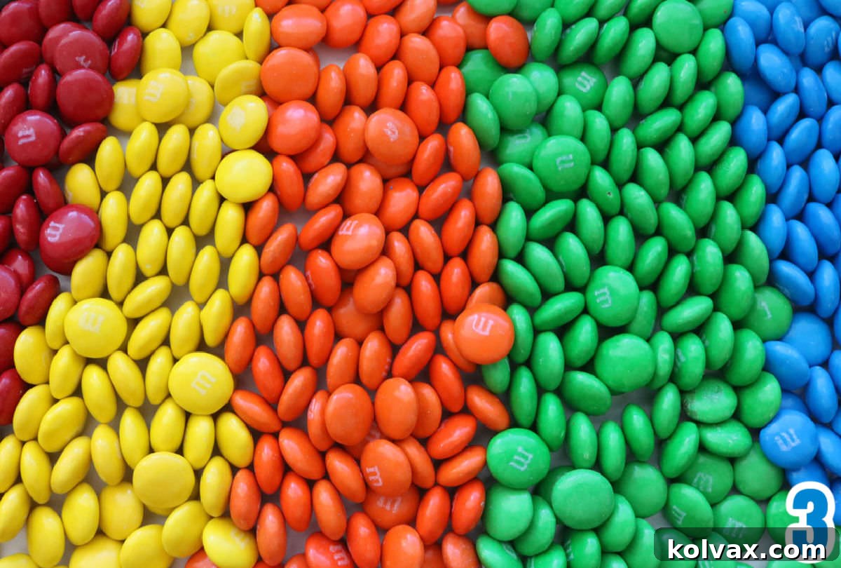 A vibrant array of M&M's meticulously arranged in a rainbow pattern across a clean white surface, showcasing the diverse colors available for decorating.
