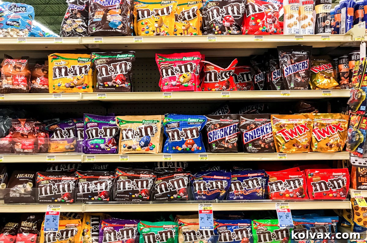 A grocery store shelf filled with bags of different types of M&M's.