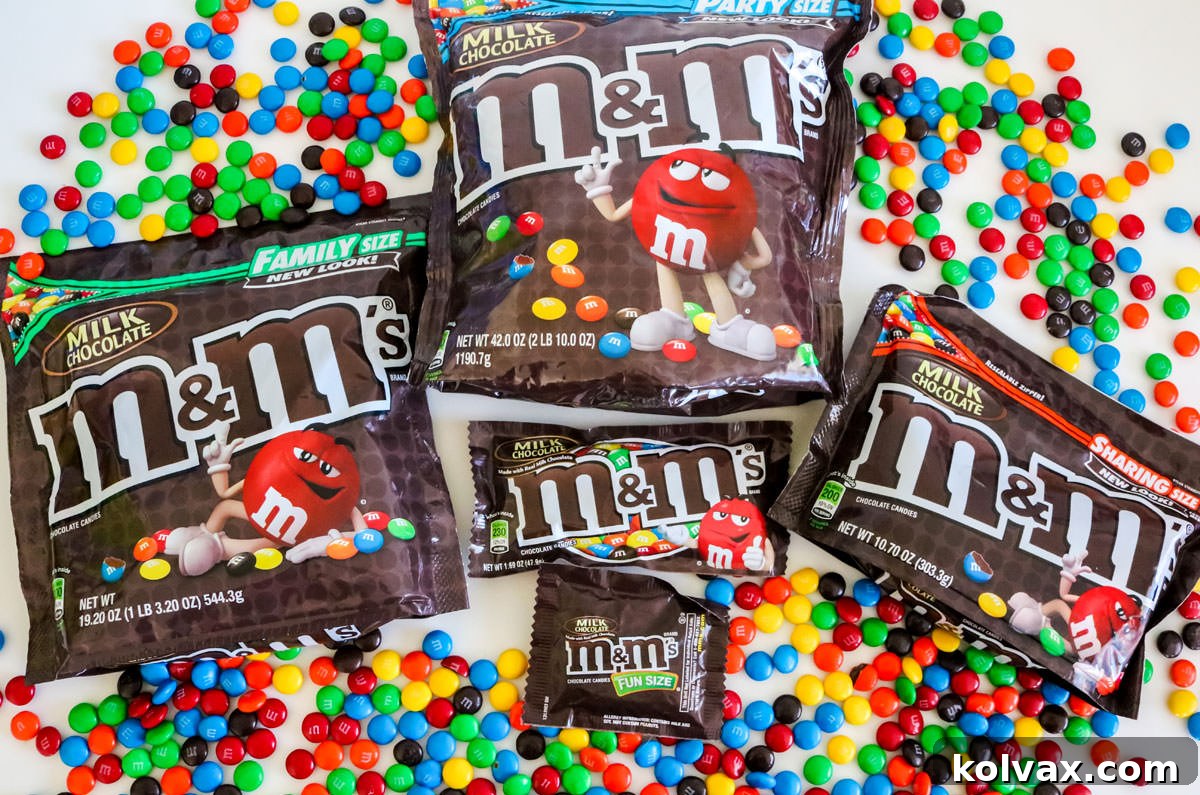 The most popular-sized bags of M&M's laying on a white table surrounded by colored M&M's.