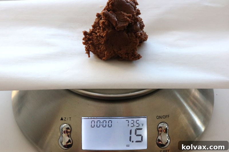 Measuring chocolate cookie dough portions precisely on a food scale to ensure uniform size, critical for even baking and consistent results.