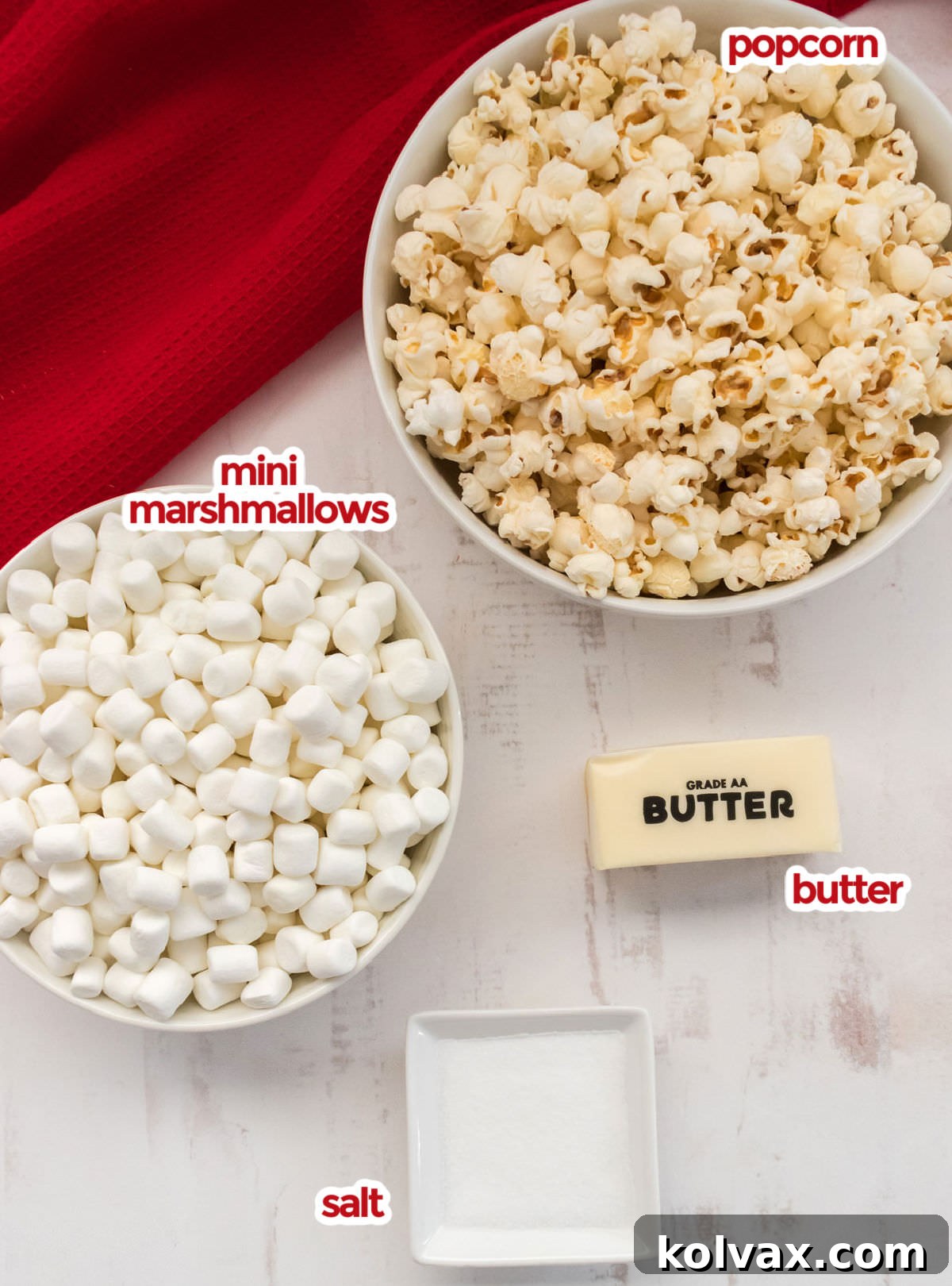 All the essential ingredients for Marshmallow Popcorn: freshly popped popcorn, a bowl of mini marshmallows, a stick of butter, and a salt shaker.