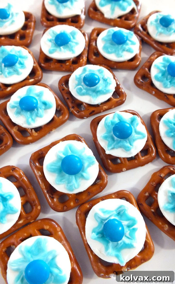 Disney Frozen Snowflake Pretzel Bites - A close-up shot of the finished sweet and salty Disney Frozen Snowflake Pretzel Bites, showcasing their intricate blue snowflake design and blue M&M center, a perfect unique dessert for any Frozen-themed party. Ideal for sharing and an easy make-ahead treat.