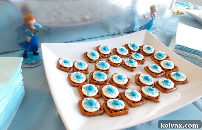 Disney Frozen Snowflake Pretzel Bites - A vibrant display of the sweet and salty Disney Frozen Snowflake Pretzel Bites artfully arranged on a dessert table, blending seamlessly with a blue ombre theme for a magical Frozen Party. These treats are a delicious and easy party snack.