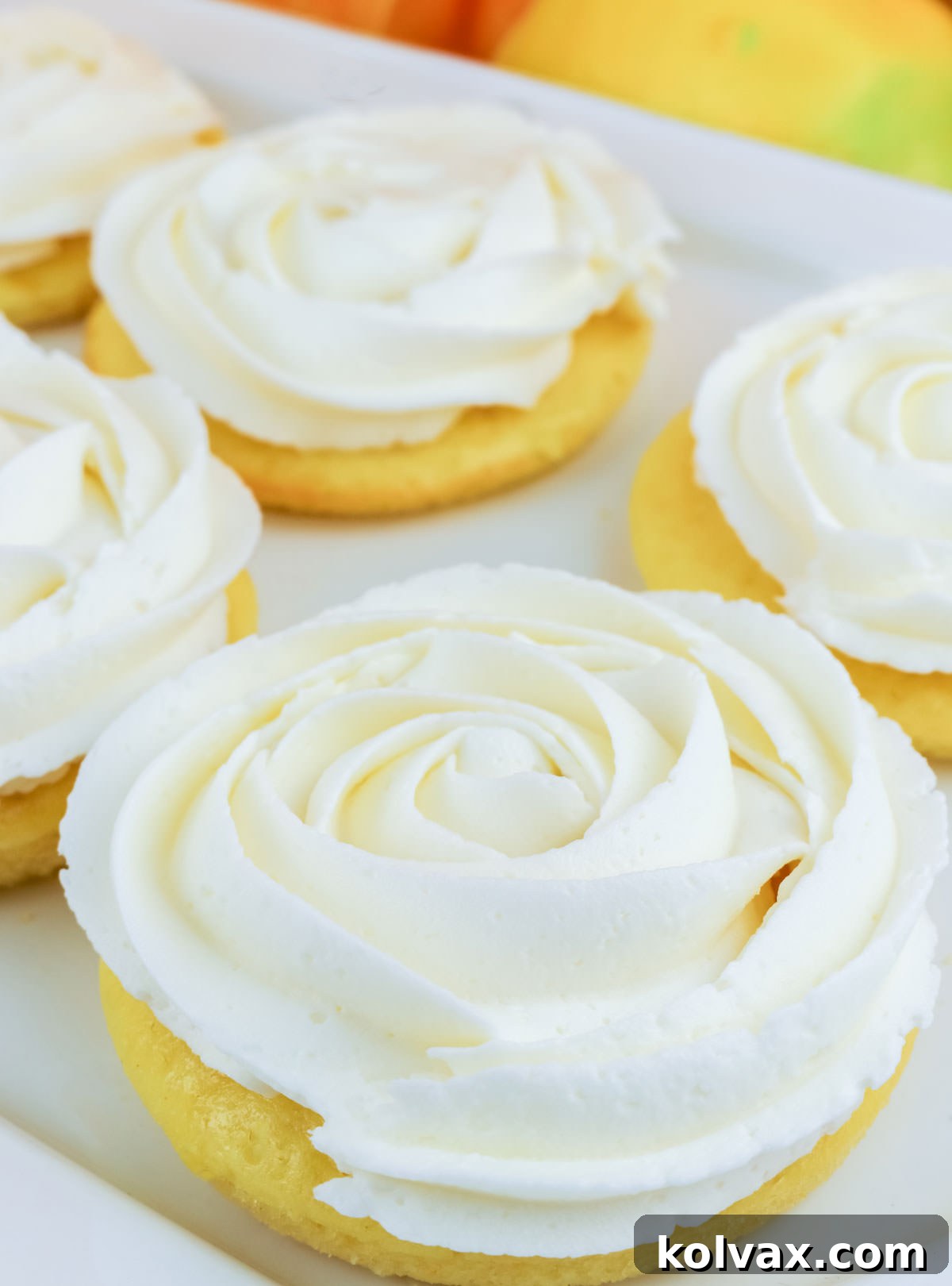 Zesty Lemon Buttercream Minis 6 A beautifully arranged batch of Lemon Mini Cakes, each adorned with creamy lemon frosting, presented on a white dessert platter, ready to be enjoyed.
