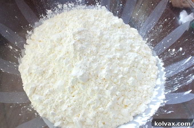 Pouring two 16 oz boxes of cornstarch into a large plastic bowl, the first step in making DIY play snow.