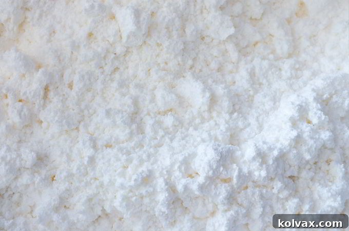 Mixing shaving cream and cornstarch by hand in a large bowl, demonstrating the kneading process for DIY play snow.