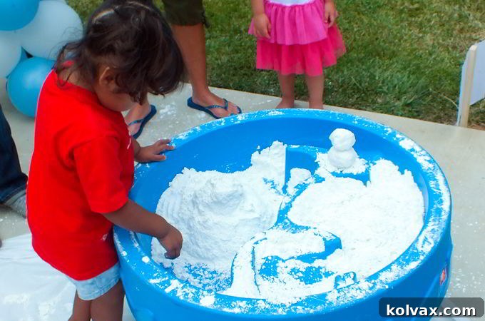 Children happily playing with DIY Play Snow at a Frozen birthday party activity station, building and exploring the snow.
