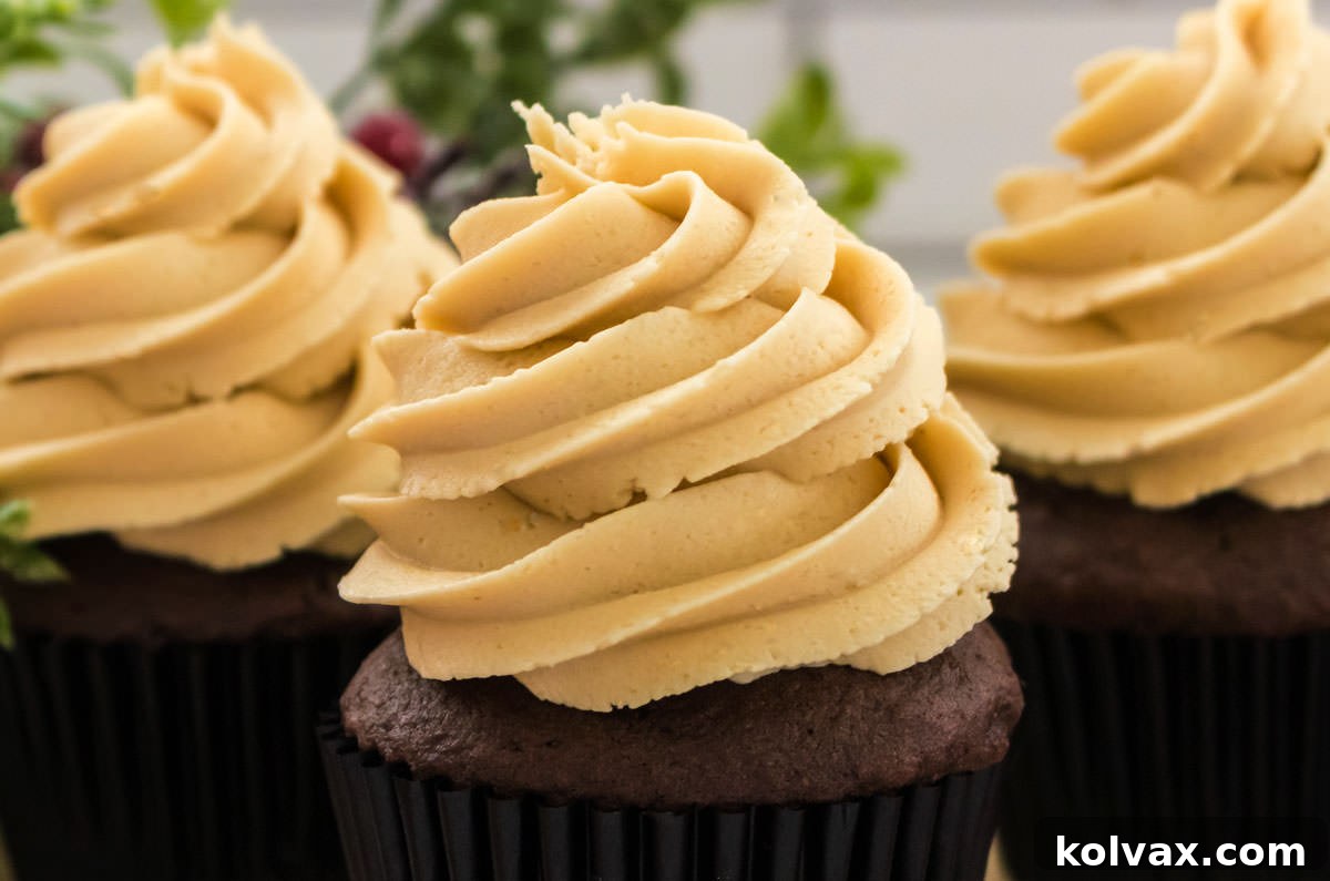 Closeup on three cupcakes topped with The Best Gingerbread Buttercream Frosting, garnished with festive sprinkles.