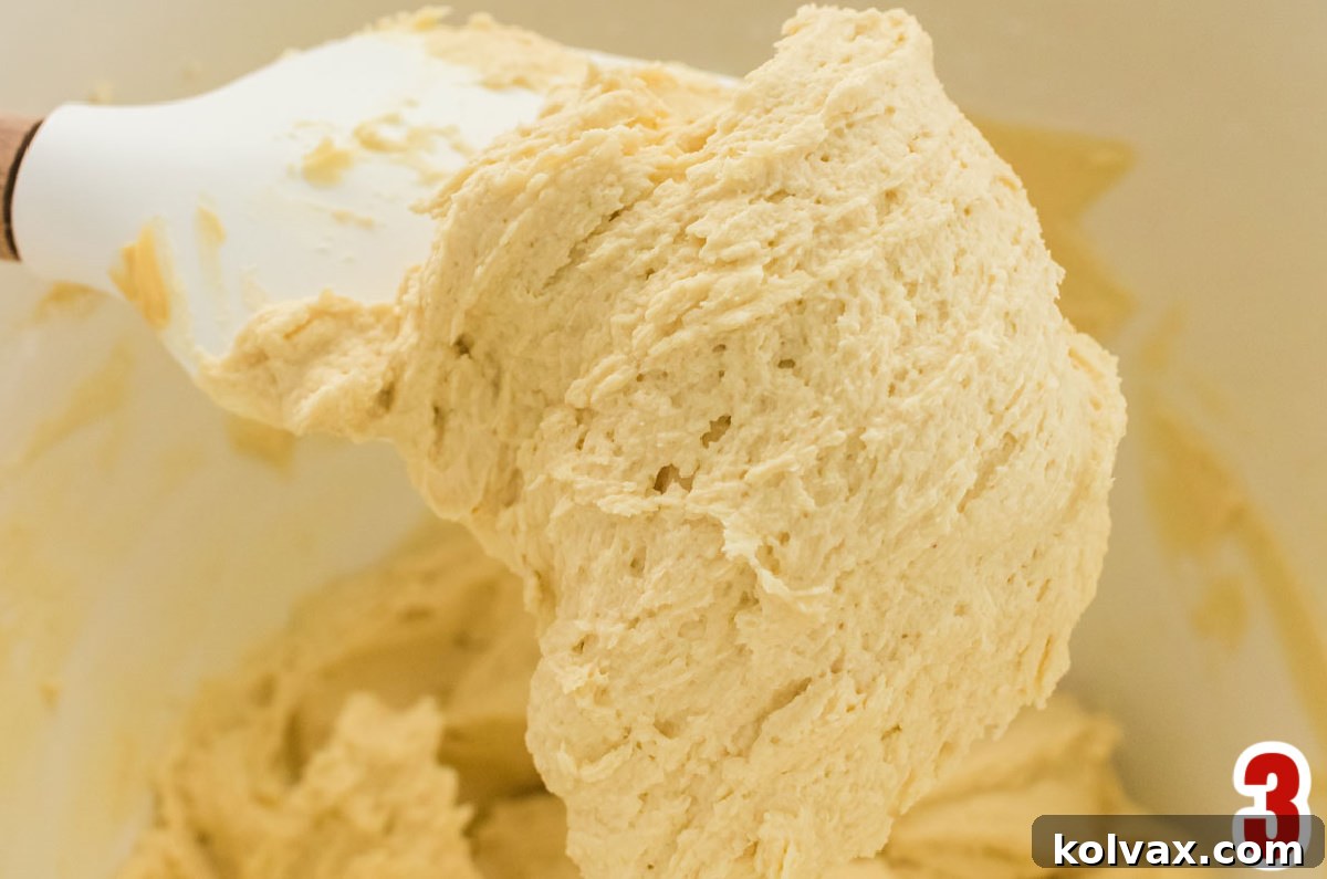 A white mixing bowl brimming with a generous batch of creamy homemade Gingerbread Buttercream Frosting.