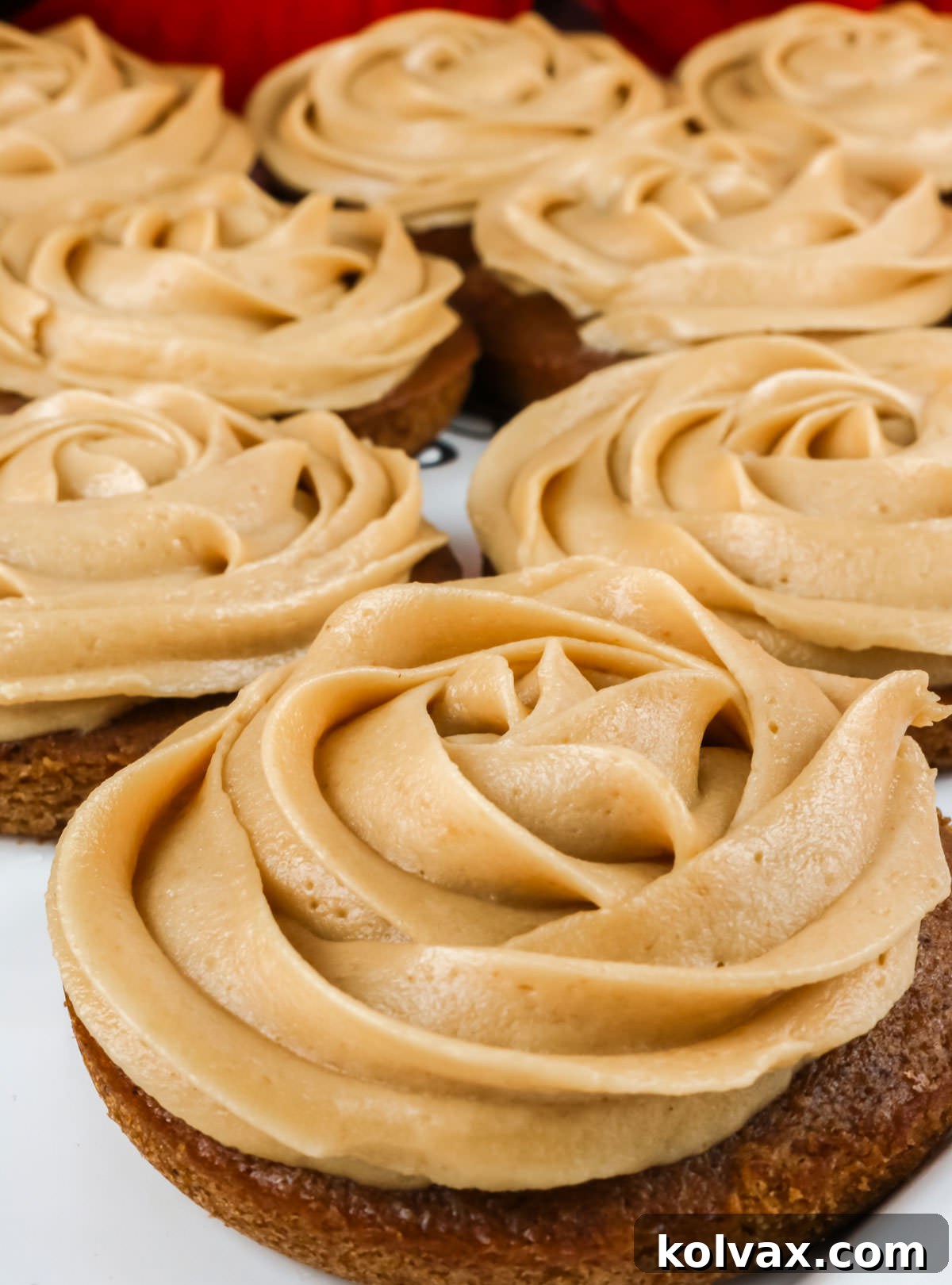 Closeup on a pristine white serving platter filled with an entire batch of beautifully decorated Gingerbread Mini Cakes, ready to be enjoyed.