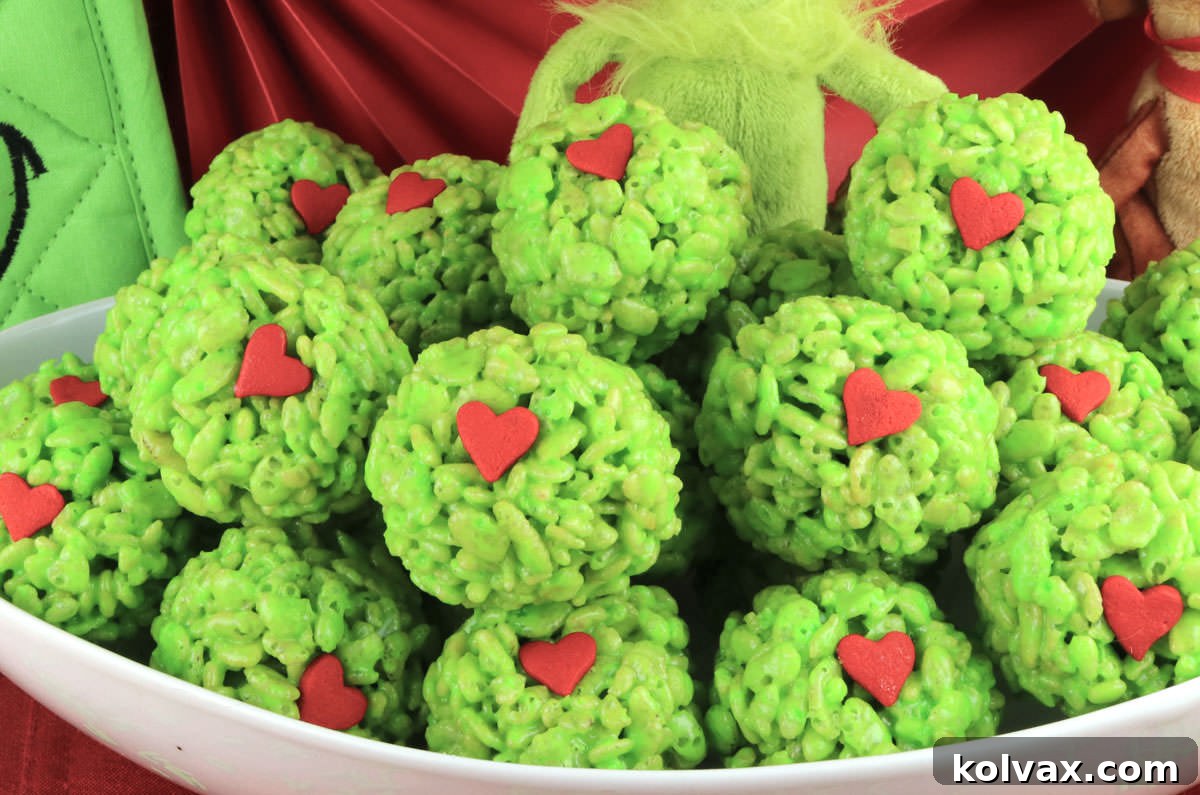 Closeup on a white serving bowl filled with a batch of Grinch Rice Krispie Treat Bites.