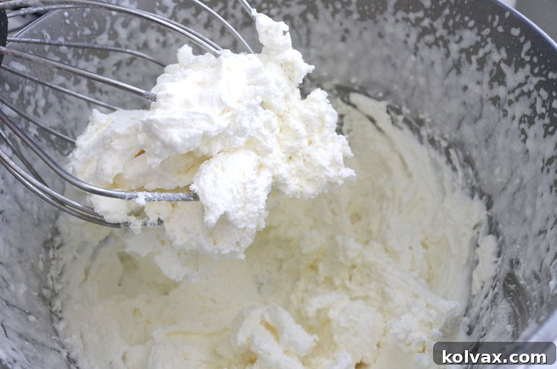 Alternating pudding mix and powdered sugar into peppermint whipped cream frosting