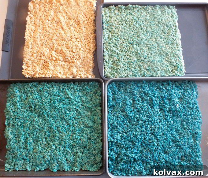 Four distinct colors of Rice Krispie Treats, including white and three shades of blue, ready for layering to create the ombre effect.