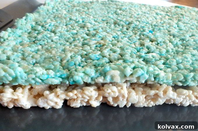 Carefully stacking the first layer of colored Rice Krispie Treats, ensuring an even base for the ombre effect.