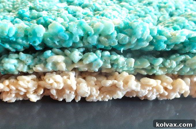 Three distinct layers of Ombre Rice Krispie Treats stacked, showcasing the progression of color from darkest to lightest blue.