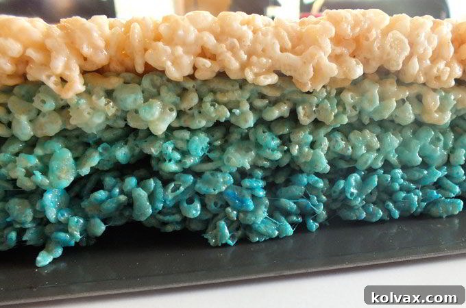 Flipping over the layered Ombre Rice Krispie Treats to reveal a smooth, pristine white top layer and a perfect gradient.