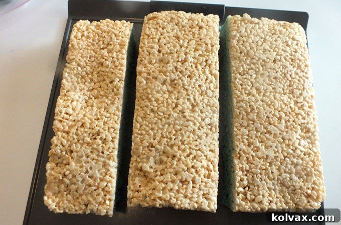 Precisely cutting the large block of Ombre Rice Krispie Treats into three equal sections before individual pieces are sliced.