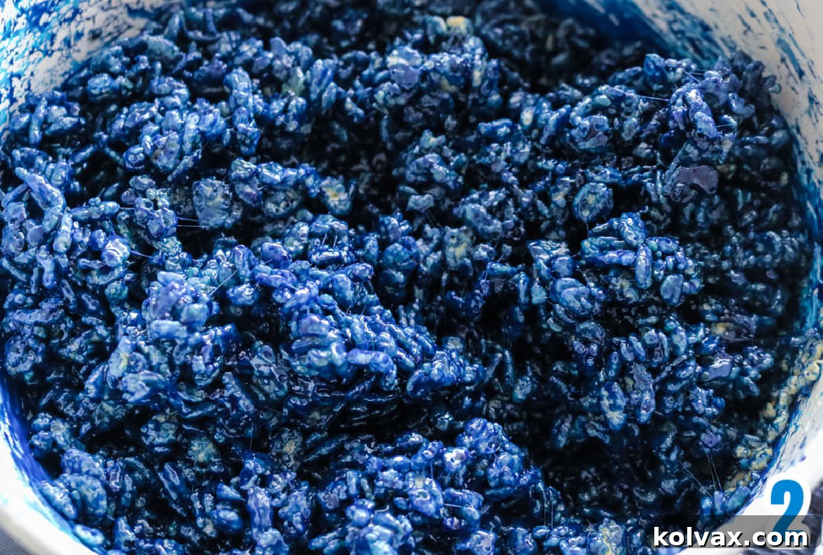 Closeup on a white sauce pan filled with blue Rice Krispie Treat mixture, after food coloring has been added.