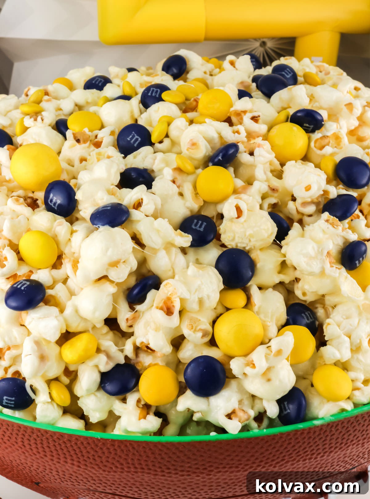 Close-up of a football-themed serving bowl filled to the brim with festive Los Angeles Rams Popcorn, ready for a party.