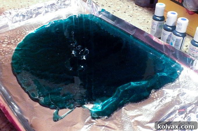 Pouring the tinted hard candy mixture carefully onto a foil-lined cookie sheet to cool and harden, creating a flat sheet of candy.