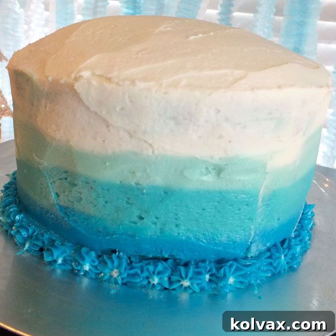 Applying decorative frosting flowers with a Wilton 1M tip at the base of the Disney Frozen Birthday Cake to hide imperfections and add elegance.