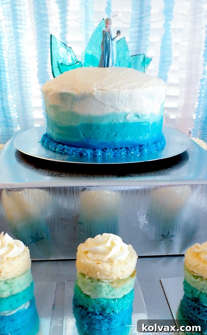 The spectacular Disney Frozen Birthday Cake, featuring captivating ombre buttercream frosting and an impressive Hard Candy Frozen Fractal Ice Castle Topper, beautifully displayed on a Frozen-themed dessert table.