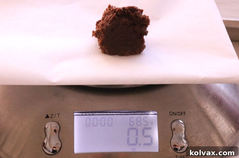 A baker carefully measuring out chocolate cookie dough balls.