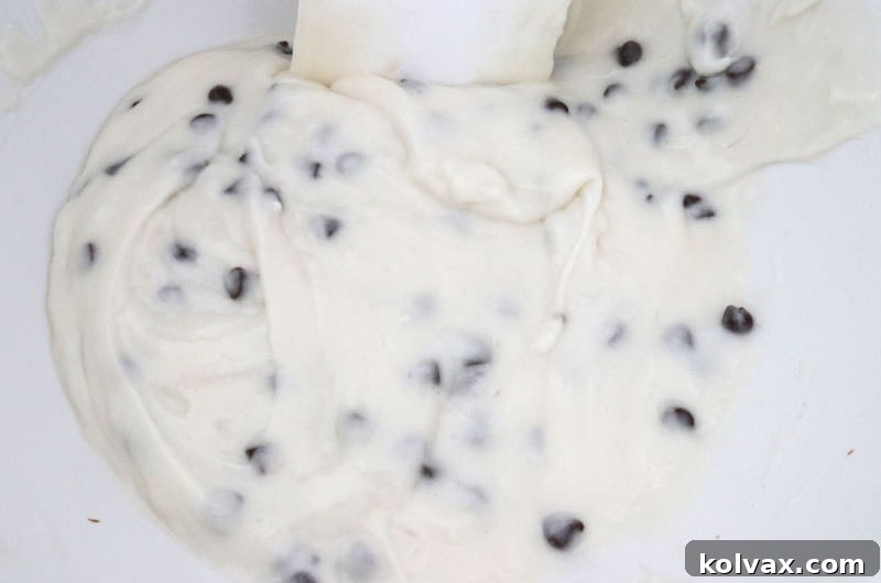 Close-up of the white cupcake batter after mini chocolate chips have been gently folded in, ready for baking.