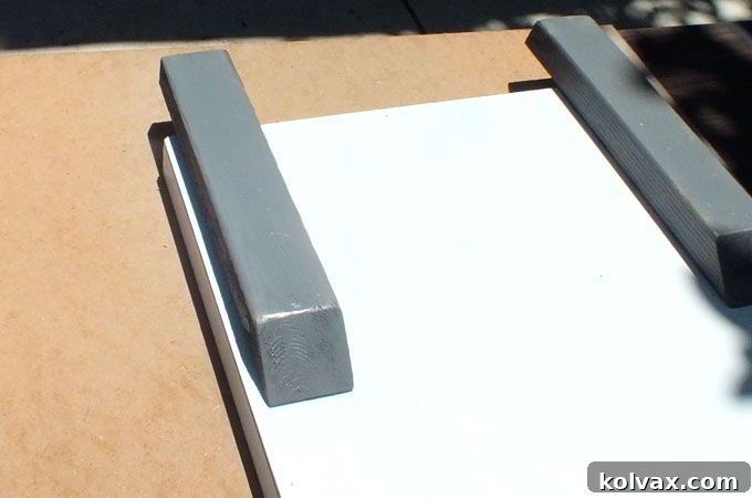 Attaching the gray-painted runners to the bottom of the DIY sled with screws