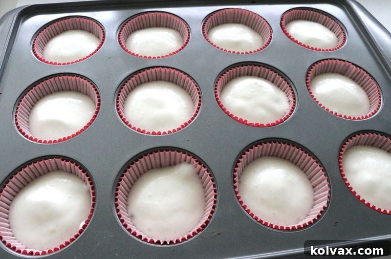 Cupcake liners filled three-quarters with Angel Food Cake batter, ready for baking.