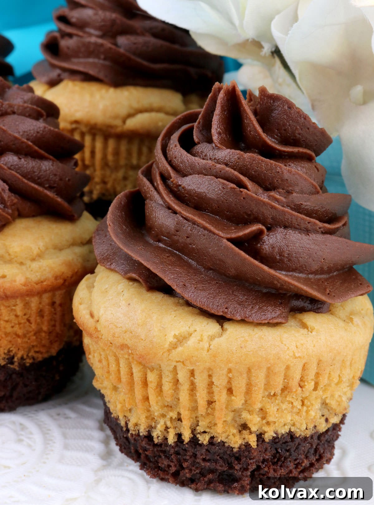 Closeup on three Peanut Butter Brownie Cupcakes sitting on a white table cloth.