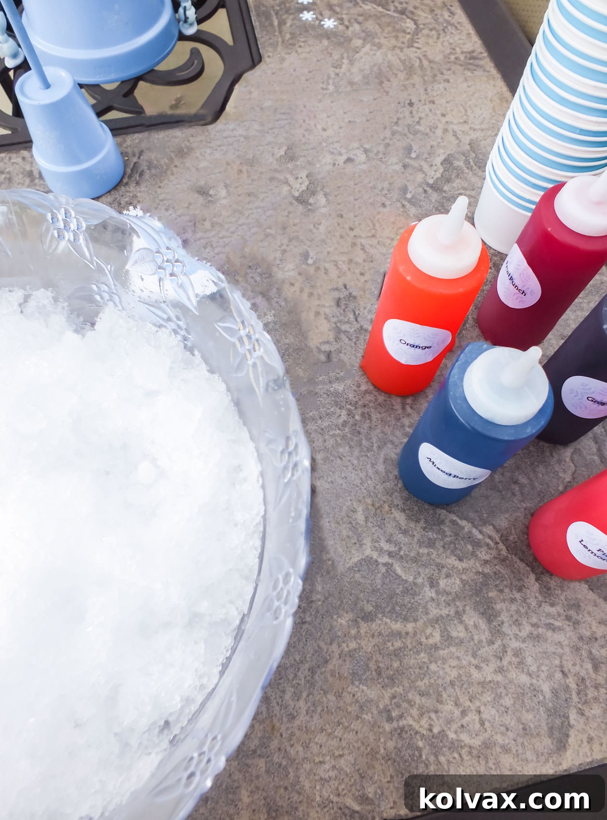 Three colorful snow cones, one with an umbrella, on a wooden table