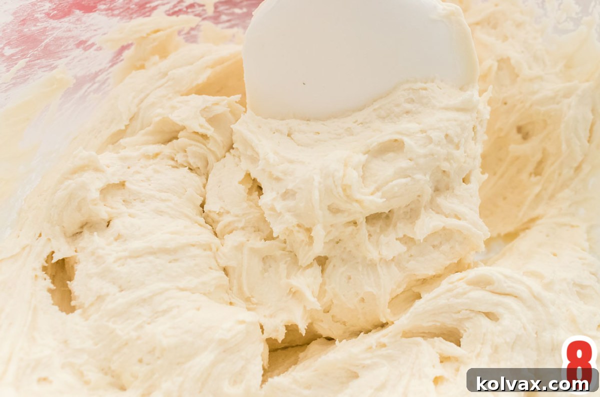 Closeup on a glass mixing bowl filled with Kahlua Frosting and a white spatula.