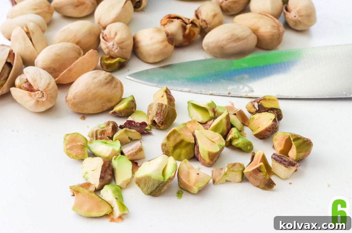 Raw pistachios, some shelled and some unshelled, scattered artfully on a white table, ready for decoration.