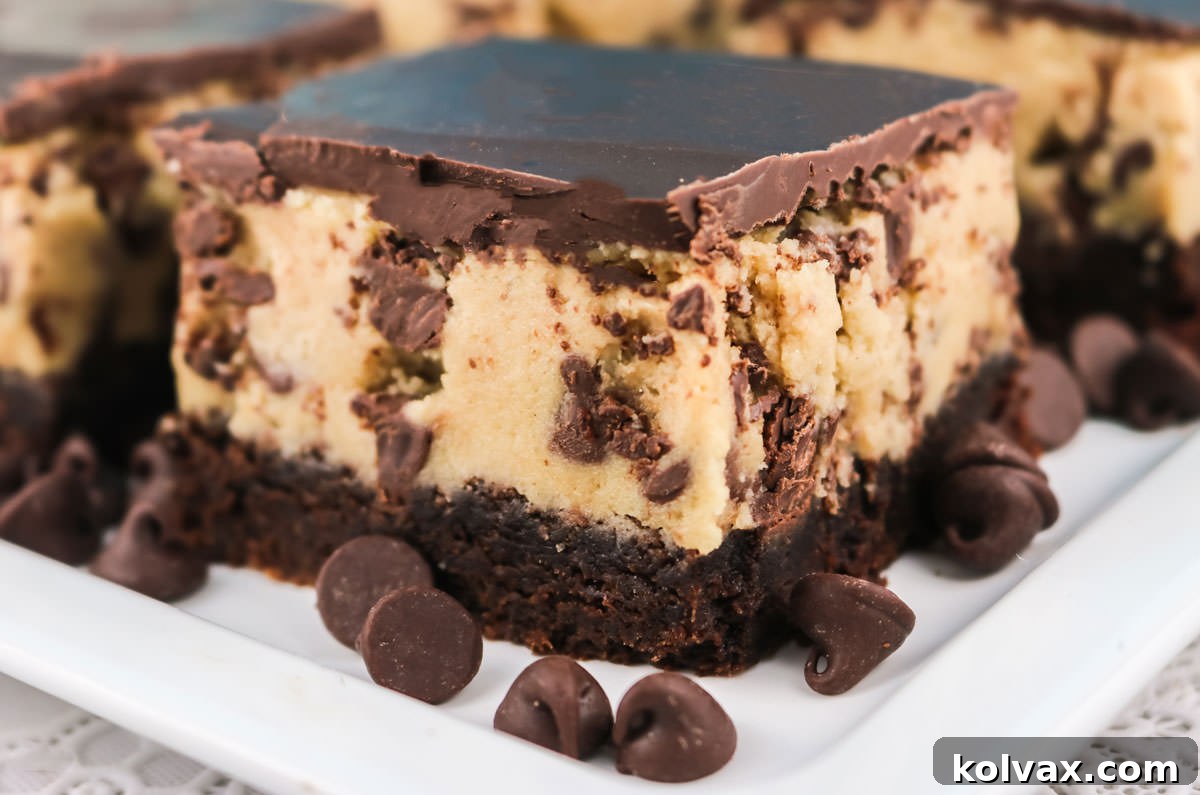 Close-up of a stack of three Cookie Dough Brownie Bars on a white dessert plate, showing the distinct layers of chocolate cookie, cookie dough frosting, and dark chocolate ganache.