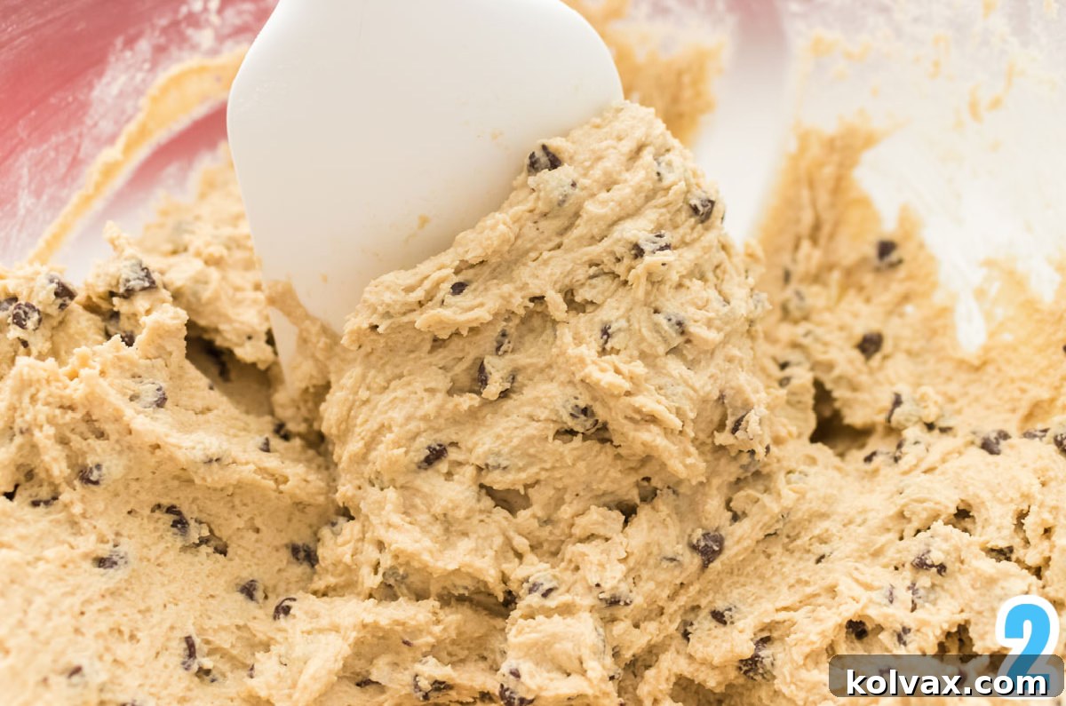 A glistening glass bowl filled with rich, creamy homemade cookie dough frosting, ready to be spread.