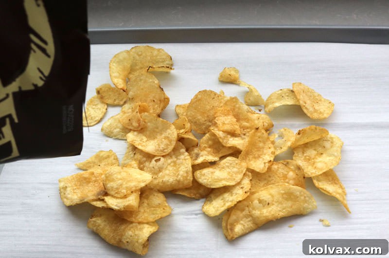 Pouring a bag of Kettle Chips onto a baking sheet lined with parchment paper.