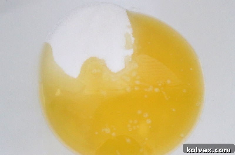 Adding melted butter and granulated sugar to a mixing bowl to start the homemade brownie batter.