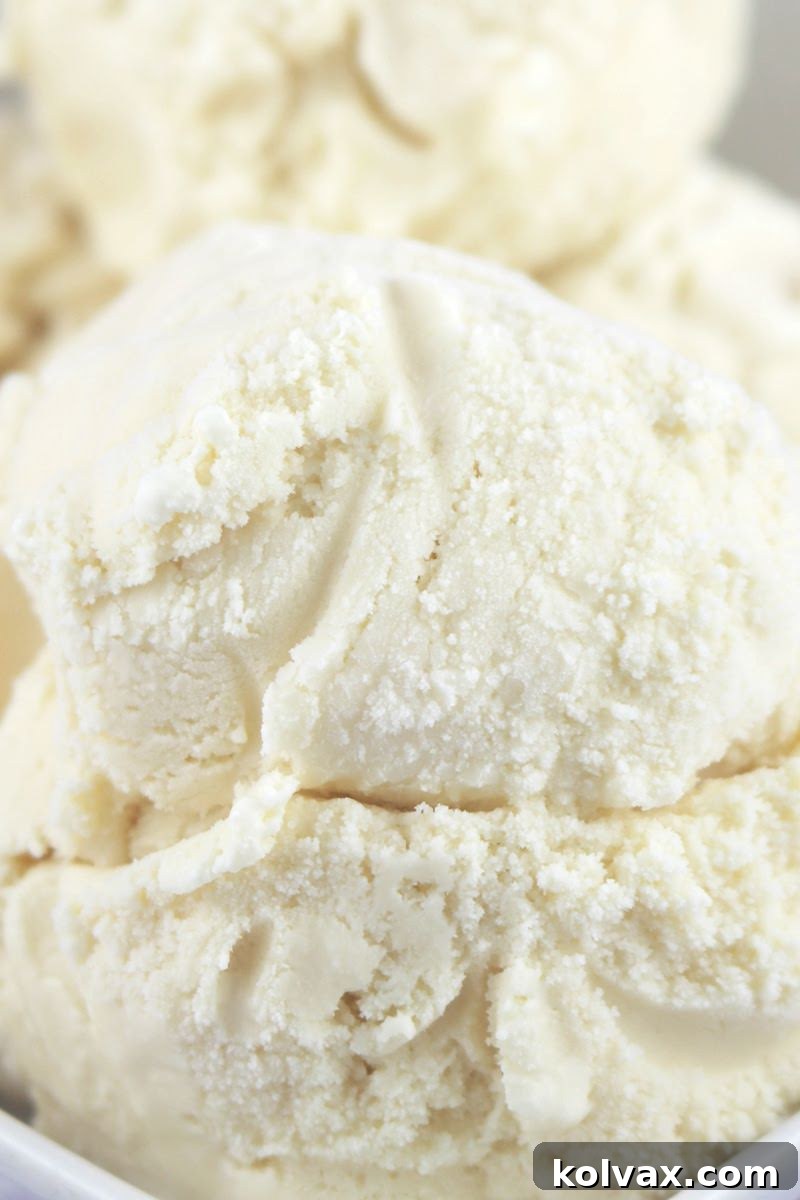 Three scoops of the best homemade vanilla ice cream, perfectly creamy and firm, served in a bowl with a spoon.