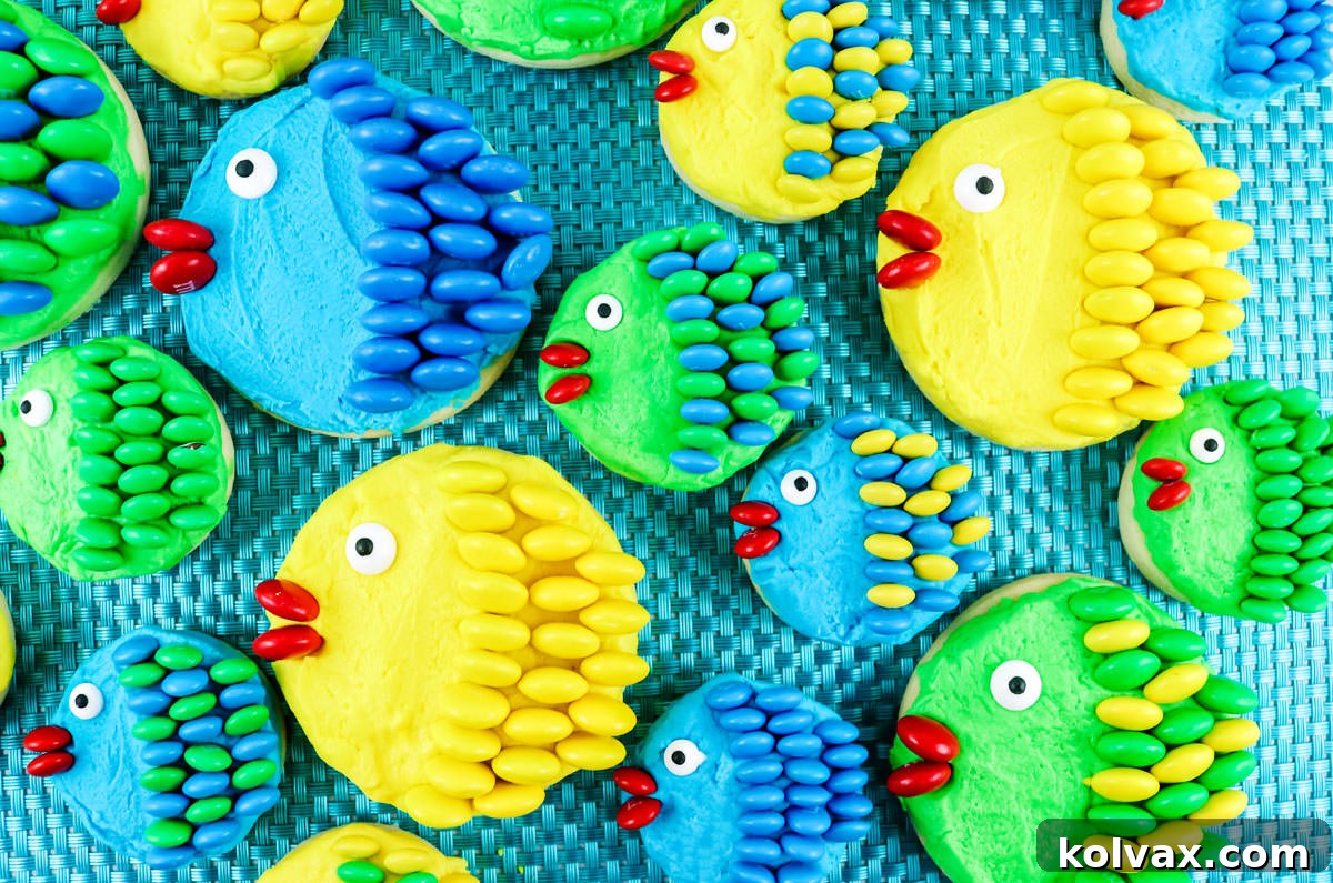 A batch of vibrantly colored Under the Sea M&M Fish Cookies arranged artfully on a blue placemat, showcasing their charming M&M scales and playful expressions.