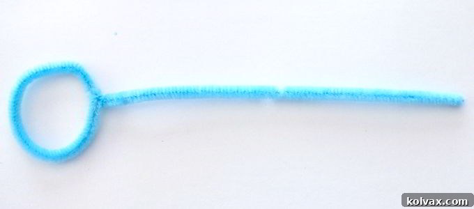 Start creating your DIY Frozen Bubble Wand by forming a perfect circular loop at one end of a light blue pipe cleaner, preparing it for bubble blowing magic.