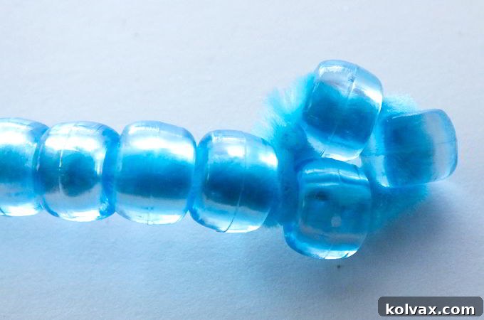 To complete your DIY Bubble Wand, twist the un-beaded end of the pipe cleaner around the last few plastic beads, forming a small, secure loop that prevents beads from falling and adds stability.