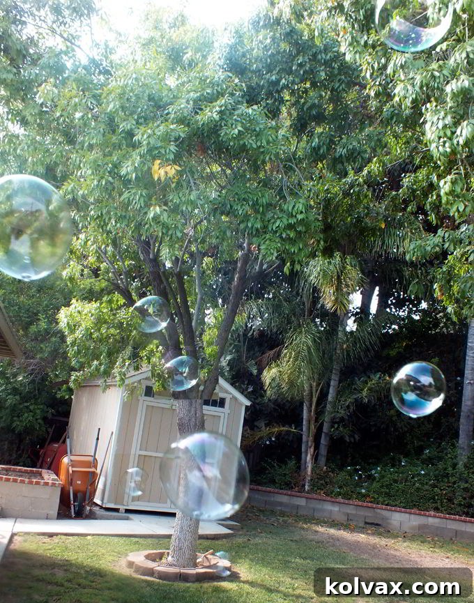 Children happily playing with Elsa Snow Bubbles at the Frozen Bubble Station during an outdoor party.